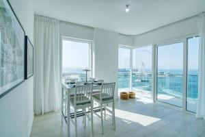 een witte kamer met een tafel, stoelen en ramen bij Stunning 2BR with Sea and Ain Dubai View at JBR in Dubai