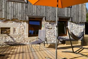 una sombrilla naranja y sillas en una terraza de madera en L'Hôtel Enfoncé, chambres d'hôtes, en Le Val-dʼAjol