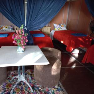 Auberge Village Paradise Valley في Tagherat Anekrim: غرفة بسريرين وطاولة مع إناء من الزهور