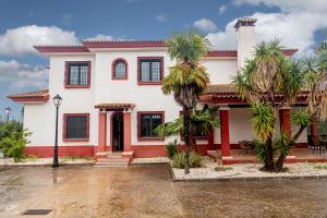 una casa bianca con palme di fronte di Finca Los Majadales ad Almodóvar del Río