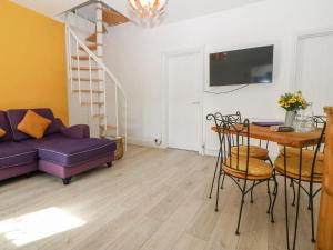 a living room with a purple couch and a table at 'Llandudno Central' - 2 Bed Luxury Flat, Close to Town and Beaches in Llandudno