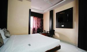 een slaapkamer met een bed en een tv aan de muur bij FabHotel Madurai in Udaipur