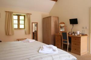 a bedroom with a bed and a desk and a television at The Ancient Mariner in Nether Stowey