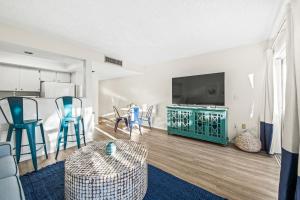 a living room with a flat screen tv and chairs at Coconuts Poolside #115 in Holmes Beach