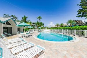 a swimming pool with chairs and tables and a fence at Coconuts Poolside #115 in Holmes Beach