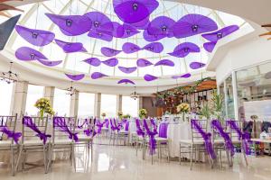 Habitación con sillas y mesas de color púrpura y sombrillas púrpuras. en TTC Hotel - Michelia, en Nha Trang