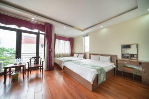 a bedroom with two beds and a desk and a television at Family Airport Hotel - 5 minutes Noi Bai in Noi Bai