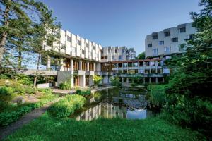 un edificio de apartamentos con un estanque frente a él en Hotel Simplicity by Bad Schönbrunn, en Menzingen