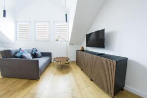 uma sala de estar com um sofá e uma televisão de ecrã plano em Apartamenty Parkowa 9 em Lesko