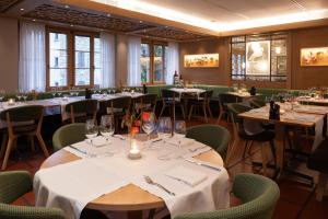 un comedor con mesas y sillas y copas de vino en Wysses Rössli Swiss Quality Hotel, en Schwyz