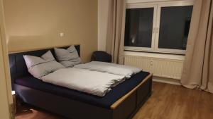 ein Bett mit Kissen darauf in einem Zimmer mit Fenster in der Unterkunft 3-Zimmer mitten in Siegburg in Siegburg