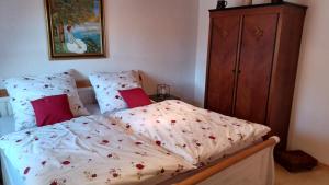 a bed with a white comforter and red pillows at Ferienwohnung Haus am Berg in Innernzell