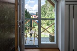 Une porte ouverte s'ouvre sur un balcon avec une chaise. dans l'établissement Peaceful, Cozy Designer Mountain Studio, à Harrachov