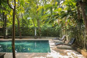 a swimming pool with two chairs and trees at Softouch Ayurveda Village Kerala in Kizhake Chālakudi