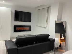 a living room with a black couch and a tv at H Pelayo Auto Check-In Rooms in Noja