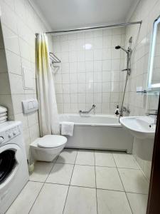a bathroom with a tub and a toilet and a sink at Arcada Apartments in Odesa