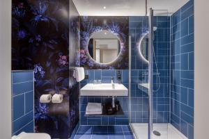 a blue tiled bathroom with a sink and a mirror at ibis Styles Rotterdam Ahoy in Rotterdam