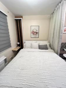 a bedroom with a large bed with white sheets at Studio Unit-8 Spatial Condo in Davao City
