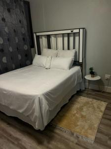 a bed with white sheets and pillows in a room at Windhoek City Center self catering appartment on independance 77 unit 95 in Windhoek