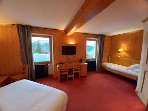a bedroom with two beds and a desk and a television at Chalet Hotel Le Mont Bisanne in Crest-Voland