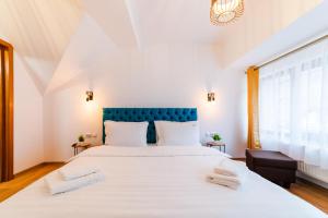 a bedroom with a large white bed with a blue headboard at Carpe Diem in Bran