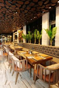 シュコダルにあるGrand Hotel Europaの木製のテーブルと椅子、植物のあるレストラン