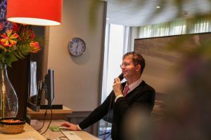een man die aan een bureau zit te praten op een microfoon bij Hotel Heemskerk in Heemskerk