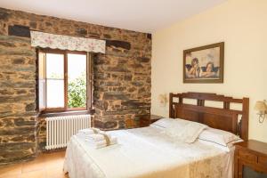 a bedroom with a bed and a brick wall at Apartamentos Turisticos A Estacion in A Pontenova