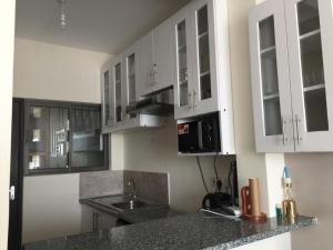 una cocina con armarios blancos y fregadero en 1255 Palm Ridge Vipingo Estate Apartments en Kilifi