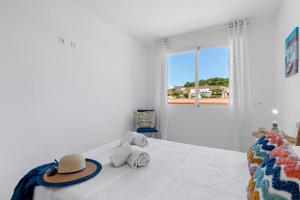 een witte slaapkamer met een bed met een hoed erop bij Apartment Manzanera 5 - PlusHolidays in Calpe