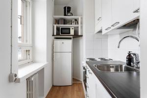 a white kitchen with a sink and a refrigerator at Nordic Studio near tram & metro 'Kallio' area in Helsinki