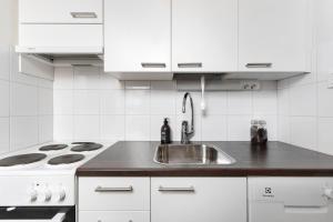 a white kitchen with a sink and a stove at Nordic Studio near tram & metro 'Kallio' area in Helsinki