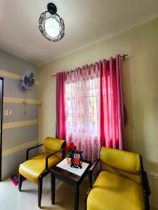 salon z 2 krzesłami, stołem i oknem w obiekcie Serene 2BR Escape: Poolside Bliss in Iloilo City w mieście Iloilo