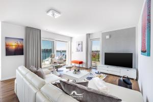 a living room with a white couch and a flat screen tv at Ebbe und Flut- direkt am Wasser, Hafenblick, Fahrstuhl, Sauna, ueberdachte Terrasse in Olpenitz