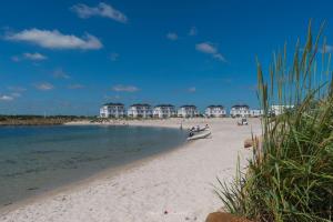 uma praia com um grupo de pessoas sentadas na areia em Ebbe und Flut- direkt am Wasser, Hafenblick, Fahrstuhl, Sauna, ueberdachte Terrasse em Olpenitz