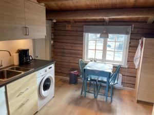 uma cozinha com uma mesa e uma máquina de lavar roupa em Maurtua - cabin in lovely surroundings em Mysusæter