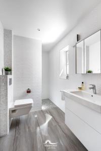 a white bathroom with a sink and a mirror at Brise- direkt am Wasser, Hafenblick, Fahrstuhl, Sauna, ueberdachter Balkon in Olpenitz