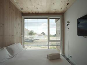 a bedroom with a white bed and a large window at Hotel Amiuka in O Pedrouzo