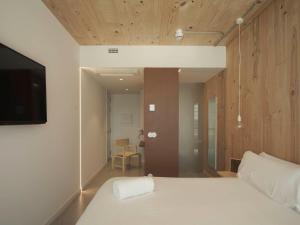 a bedroom with a white bed and a television at Hotel Amiuka in O Pedrouzo