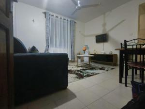 Joly Apartments, Nyali Mombasa في مومباسا: غرفة معيشة مع أريكة وتلفزيون