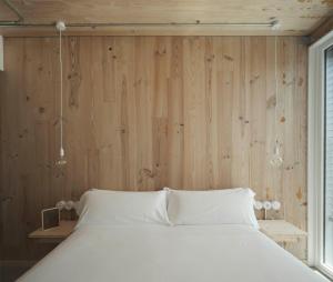 a bedroom with a white bed and a wooden wall at Hotel Amiuka in O Pedrouzo