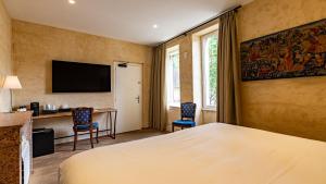 um quarto de hotel com uma cama, uma mesa e cadeiras em Les Remparts Hôtels et Demeures Historiques em Beaune