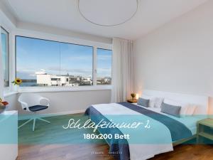 a bedroom with a bed and a large window at Harbour Lodge: Meerblick, Terrasse, Balkon, finnische Sauna, Kaminofen in Olpenitz