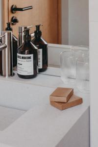 a bathroom counter with two bottles of soap and a soap holder at Hotel Moderne in Porto-Vecchio