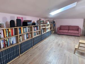 a library with shelves of books and a red couch at La Casa Rosa in Burgos