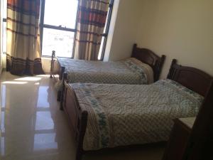 2 aparte bedden in een slaapkamer met een raam bij Newcenter Suites in Tanger