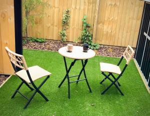 two chairs and a table with a cup on top of grass at Sunny Oasis- Modern Loft Hidden on Cashel in Christchurch