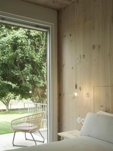 a bedroom with a bed and a chair next to a window at Hotel Amiuka in O Pedrouzo