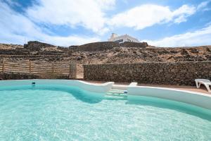 a large swimming pool with a rock wall at Playa Marina Eco Beach and Pool Bungalow Mala View in Arrieta