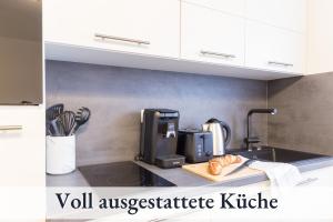ビーベラハ・アン・デア・リスにあるRelaxApartment 2 Massagesessel SmartTV Kücheの- キッチンカウンター(コーヒーメーカー、カッティングボード上のパン付)